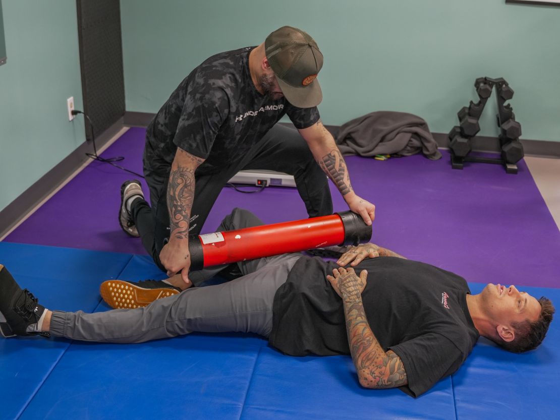 Founder Conrad Daniel delivering personalized therapeutic care at Truly Heal Wellness, Akron, Ohio. Image shows Conrad guiding a client through assisted leg manipulation using body tempering—highlighting his integrative approach to musculoskeletal recovery, mobility enhancement, and preventative wellness.